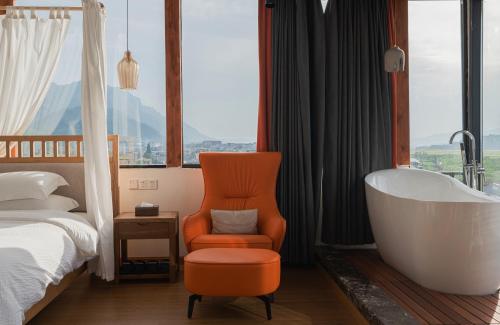 a bathroom with a tub and a chair and a bed at 张家界天门山伴田居民宿 in Zhangjiajie
