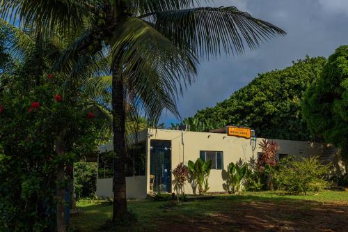 a white building with a palm tree in front of it at Pousada Shalon Adonai Noronha in Fernando de Noronha