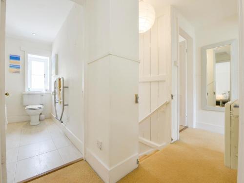 ein weißes Badezimmer mit Toilette und Flur in der Unterkunft 4 Coastguards Cottage in Hope-Cove