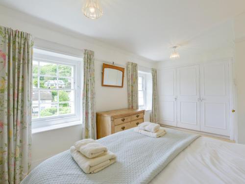 1 dormitorio con 1 cama con 2 toallas en 4 Coastguards Cottage, en Hope-Cove