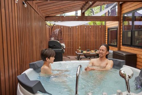 a man and a boy in a hot tub at サウナバーベキュージャグジー完全貸し切りという贅沢大人の秘密基地#01 in Miyota