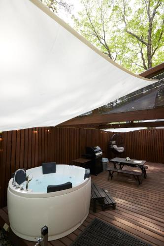 a bath tub sitting on a deck next to a piano at サウナバーベキュージャグジー完全貸し切りという贅沢大人の秘密基地#01 in Miyota
