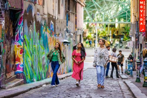 three women walking down a street with graffiti at YHA Melbourne Central in Melbourne
