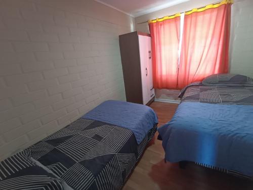 a bedroom with two beds and a red window at Hostal JV QUILLOTA AMOBLADA in Quillota