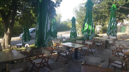 een groep tafels en stoelen met groene parasols bij Ваканционно селище СБХ in Shkorpilovtsi