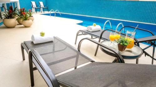 um pátio com uma mesa e cadeiras ao lado de uma piscina em TH Flats Governador Valadares em Governador Valadares