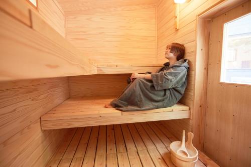 a woman sitting in the inside of a sauna at サウナ・ジャグジー・完全貸し切りという贅沢　大人の秘密基地　Tiny Cabin TATEGU#02 in Miyota
