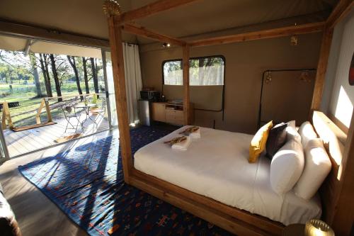 a bedroom with a bed in a room with a balcony at Two Fat Blokes Outback Adventure Glamping in Pokolbin