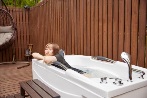 a little girl laying in a bath tub at サウナ・ジャグジー・完全貸し切りという贅沢　大人の秘密基地　Tiny Cabin TATEGU#02 in Miyota