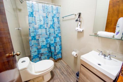a bathroom with a toilet and a sink and a shower at Steps to the beach ocean view balcony in Tijuana