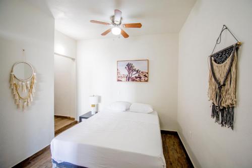 a white bedroom with a bed and a ceiling fan at Steps to the beach ocean view balcony in Tijuana