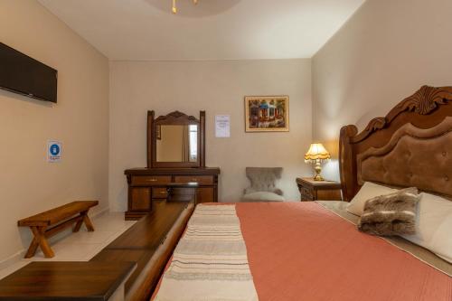 a bedroom with a bed with a dresser and a mirror at Hostería Casa Marquez in León