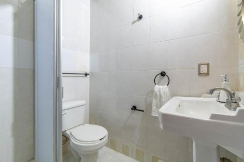 a white bathroom with a toilet and a sink at Hostería Casa Marquez in León