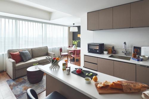 a kitchen and living room with a couch and a table at Citadines Harbour Front Yokohama in Yokohama