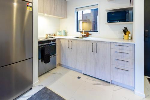 una cucina con armadi bianchi e frigorifero in acciaio inossidabile di 1 bedroom 1 bath, Executive escape, Northlands Mall a Christchurch