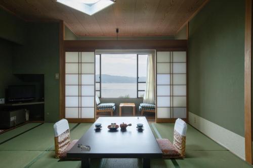 諏訪市にあるホテルすわ湖苑のテーブルと椅子、大きな窓が備わる客室です。