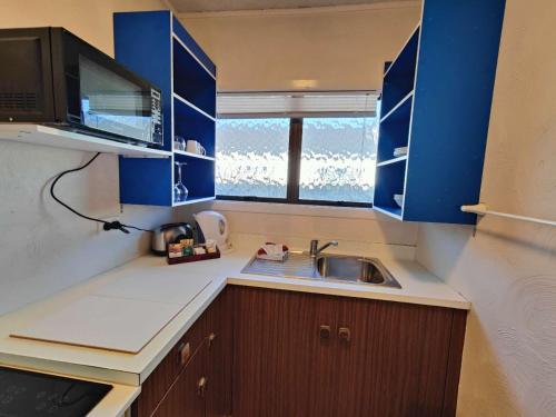 a small kitchen with blue cabinets and a sink at Kings Court Motor Lodge in Hamilton