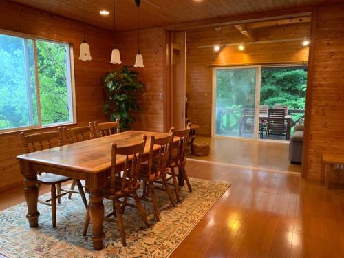 ein Esszimmer mit einem Holztisch und Stühlen in der Unterkunft 4月リニューアルOpen! 全室エアコン完備! Deerview Lodge 山中湖 in Yamanakako