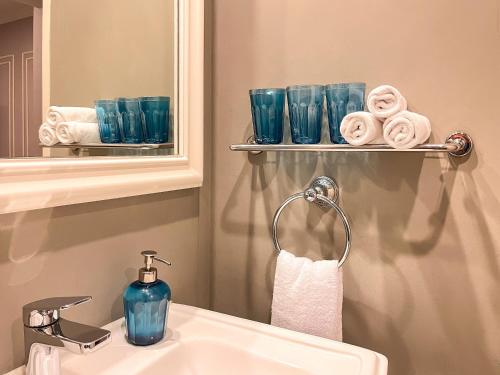 a bathroom with a sink and blue glasses and a mirror at Ashley Sabang Jakarta in Jakarta