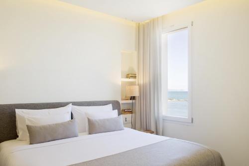 a bedroom with a large white bed with a window at Hostal Empúries in L'Escala
