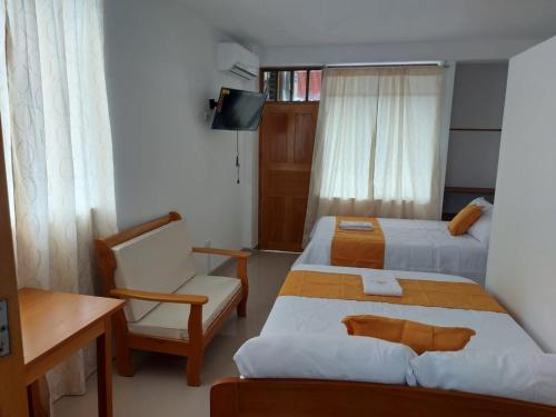 una habitación de hotel con 2 camas y una silla en Majestic Mical, en Yurimaguas
