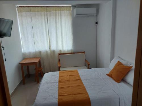 a bedroom with a bed and a chair and a table at Majestic Mical in Yurimaguas