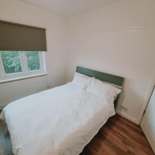 a white bed with a green headboard in a bedroom at double room in Thornton Heath