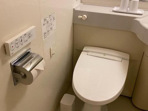 uma casa de banho com um WC e um dispensador de papel higiénico em Smile Hotel Nagoya Sakae em Nagoia