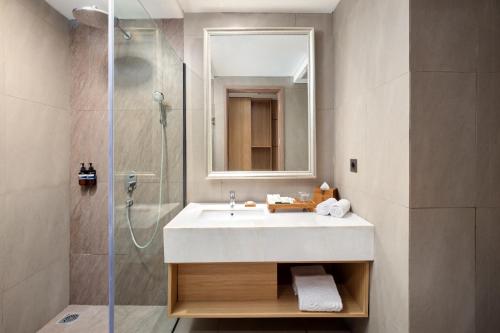 ein Badezimmer mit einem weißen Waschbecken und einer Dusche in der Unterkunft Sima Sumba Hotel 