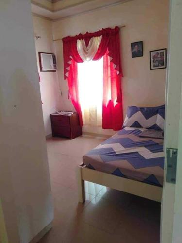 a bedroom with a bed and a window with red curtains at Room In Lobo Triple N Homestay 2nd N in Soloc