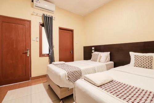 a hotel room with two beds and a door at Omah Rohadi Syariah by Ndalem Beong in Borobudur