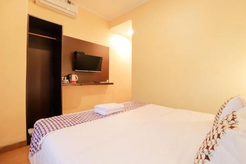a bedroom with a bed and a tv on the wall at Omah Rohadi Syariah by Ndalem Beong in Borobudur
