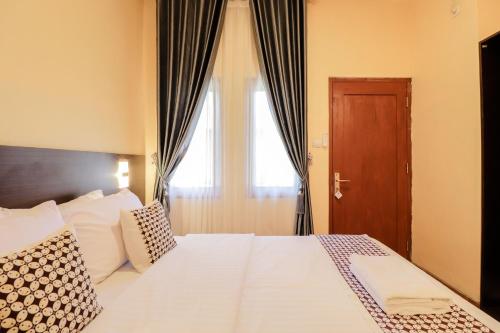 a bedroom with a bed with white sheets and a window at Omah Rohadi Syariah by Ndalem Beong in Borobudur