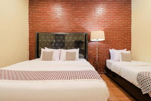 two beds in a room with a brick wall at Omah Rohadi Syariah by Ndalem Beong in Borobudur