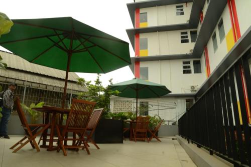 a table and chairs with umbrellas on a balcony at Front One Hotel Pasir Koja Bandung in Bandung