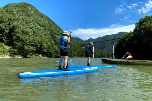 two men are standing on a paddle board in the water at Iwaiyado Jyuan Nikko Kawaji onsen in Nikko