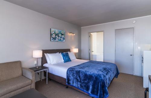 a bedroom with a bed and a couch and a chair at Twin Peaks Lakeside Inn in Taupo