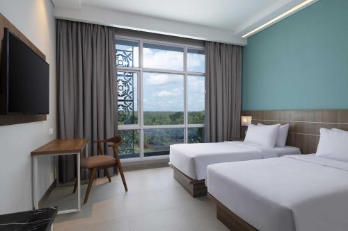 a hotel room with two beds and a window at Hotel Santika Gunungkidul in Siyonokulon