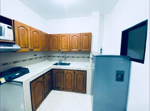 uma cozinha com armários de madeira e um frigorífico azul em Apartamento confortable y cálido em Itagüí