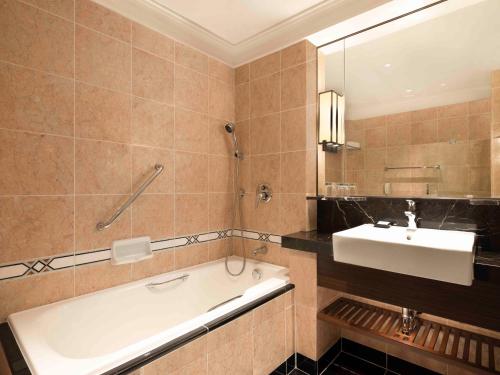 a bathroom with a bath tub and a sink at Sheraton Saigon Grand Opera Hotel in Ho Chi Minh City