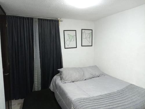 uma cama num quarto com duas fotografias na parede em Departamento Cerca del Aeropuerto/ Buena Ubicación em Cidade do México