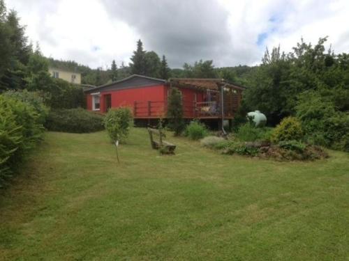 a yard with a red house in the background at Ferienhaus in einer Feriensiedlung auf dem Eichenberg mit Terrasse und Grill in Michaelstein