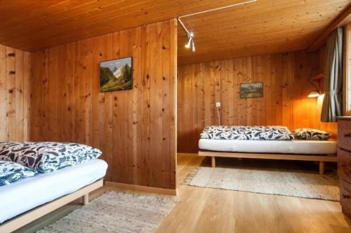 two beds in a room with wooden walls at Chalet Varga in Hasliberg