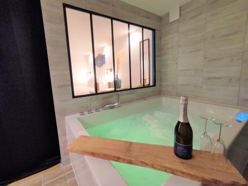 eine Badewanne mit einer Flasche Champagner in der Unterkunft Maison de ville, SPA Balnéo, 2 suites parentales in Vichy