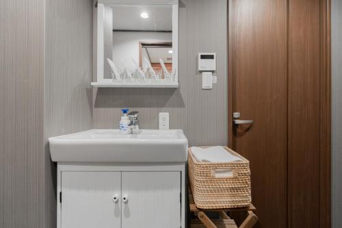 La salle de bains est pourvue d'un lavabo blanc et d'un miroir. dans l'établissement 桜Inn-通天閣403, à Osaka