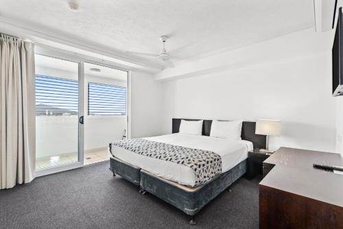 a white bedroom with a bed and a window at Cairns Central Plaza Apartment Hotel Official in Cairns