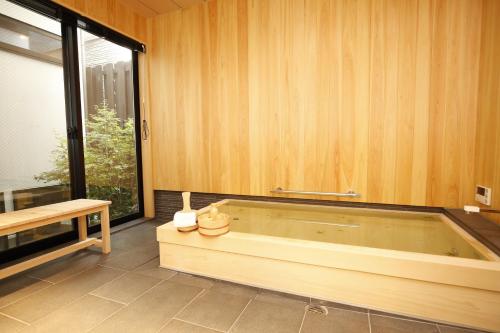 una vasca da bagno in una camera con pareti in legno di Uji-Ichibanyado-Nigauri a Ogurachō