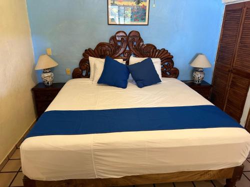 1 dormitorio con 1 cama grande con almohadas azules en Vallarta Sun Suites en Puerto Vallarta
