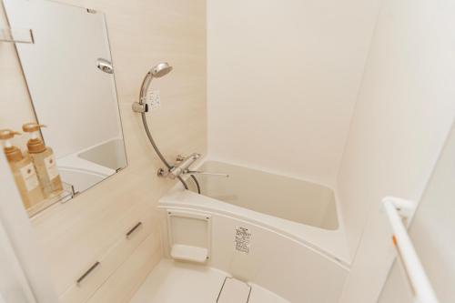 a white bathroom with a shower and a sink at 川HOUSE黒門 in Osaka