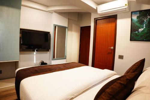 a bedroom with two beds and a flat screen tv at Dream Hotel - Richmond in Bengaluru